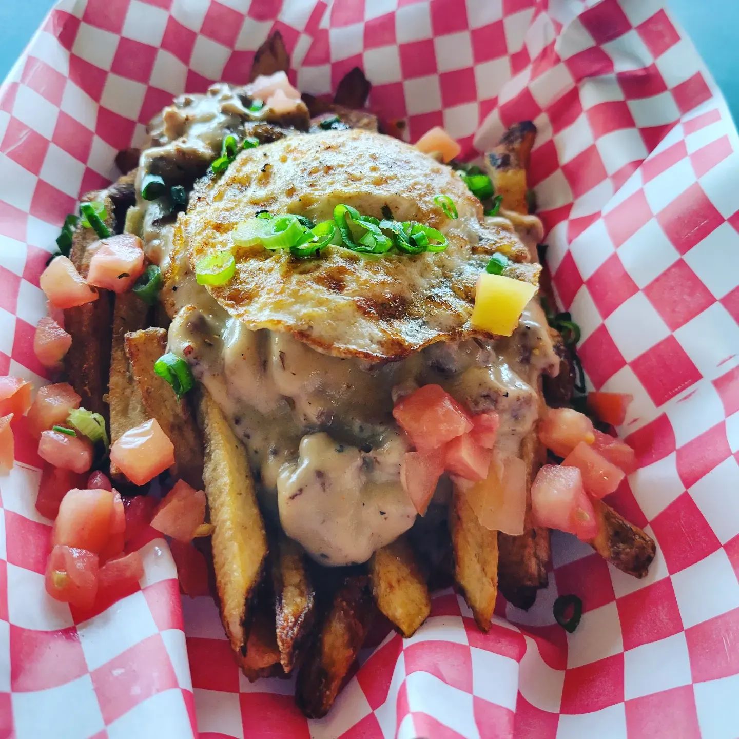 Loaded fries with gravy, a fried egg, and diced tomato